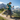 AscendLite - Pair of Feather Light Carbon Hiking Poles: hiker with backpack using trekking poles on alpine trail.
